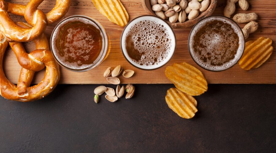 Lager beer from Little Miami Brewing Co. served with pretzels, chips, and nuts on a stone table in Milford, Ohio.