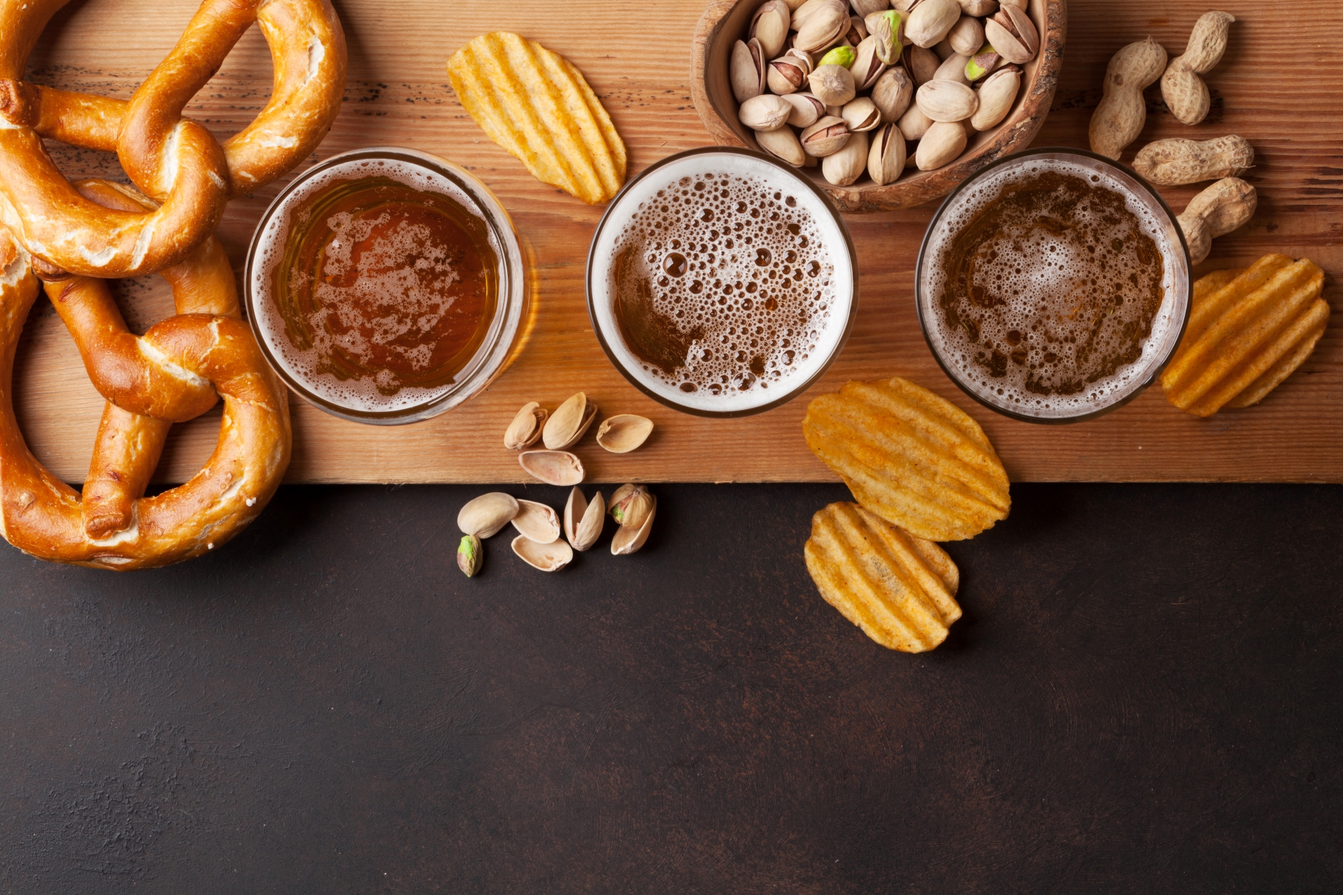 Lager beer from Little Miami Brewing Co. served with pretzels, chips, and nuts on a stone table in Milford, Ohio.