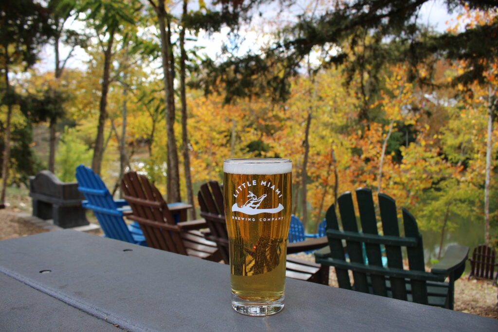 pint glass of Little Miami Brewing Company A pint glass of Little Miami Brewing Company beer on a table overlooking a fall foliage view.