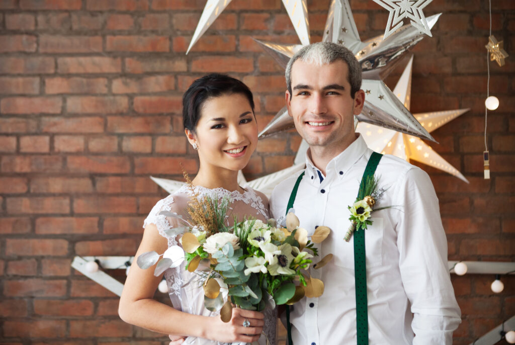 Couple posing at a brewery wedding Couple posing at a brewery wedding decorated with creative wedding themes, featuring rustic brick walls and star-shaped lights.