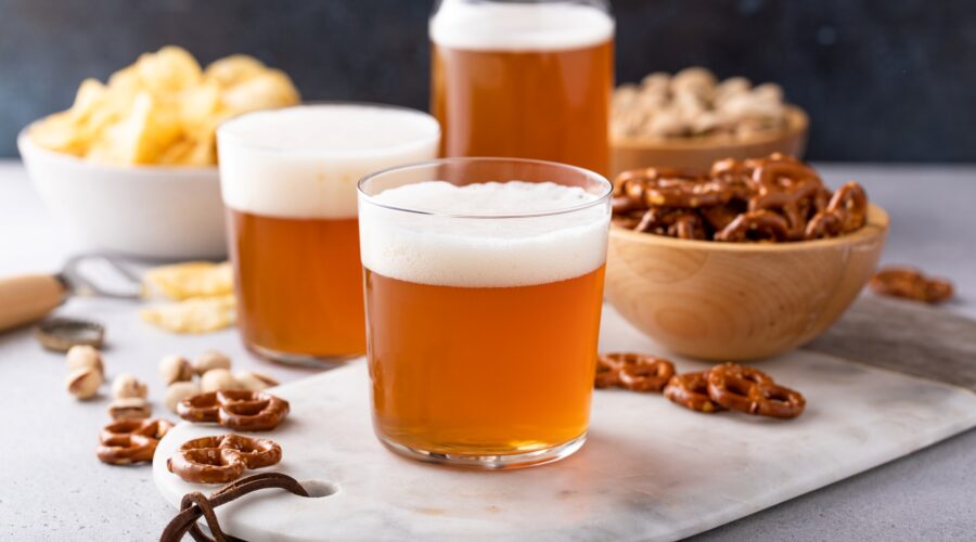 Shot of traditional lager beer in glasses with snacks on the side.