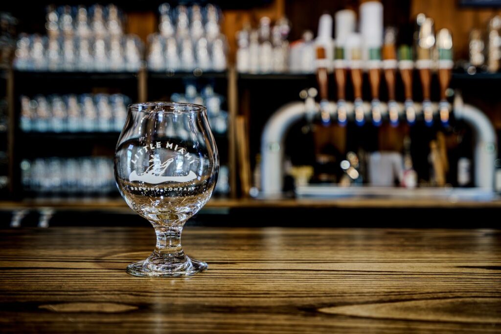 Empty Little Miami Brewing Company beer glass resting on a wooden bar top in Cincinnati taproom.