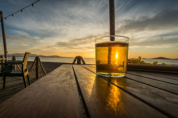 Shot of a glass of ale beer on a wooden plank against a scenic view.