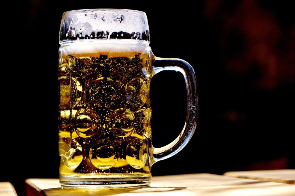 A close-up shot of a glass of beer with a foam head and bubbles inside.