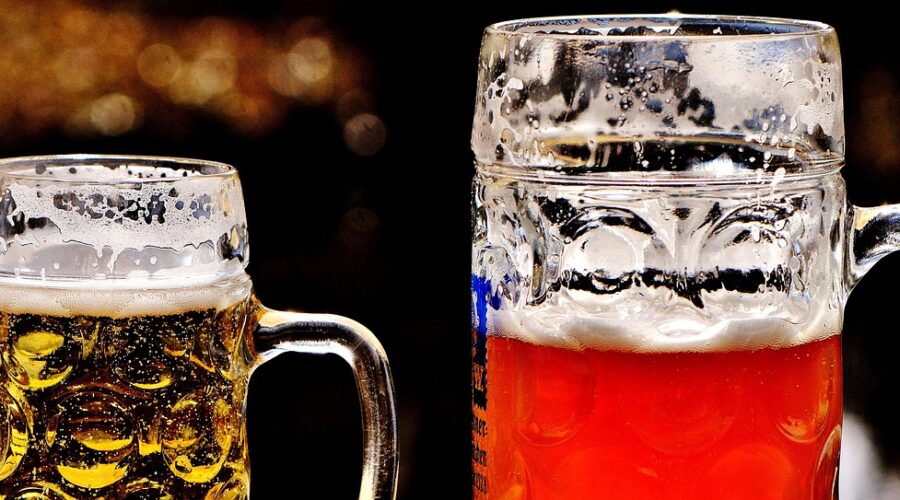 Close-up shot of two jugs of beer; one is a lager and the other an ale.
