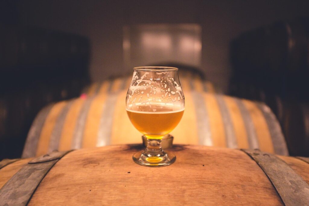 A shot of a glass of stout beer on a wooden barrel.